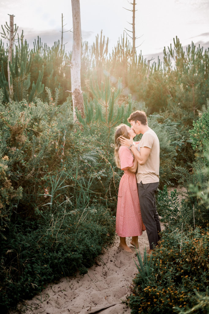 Un homme et une femme s'embrassant en forêt sous les rayons du soleil.