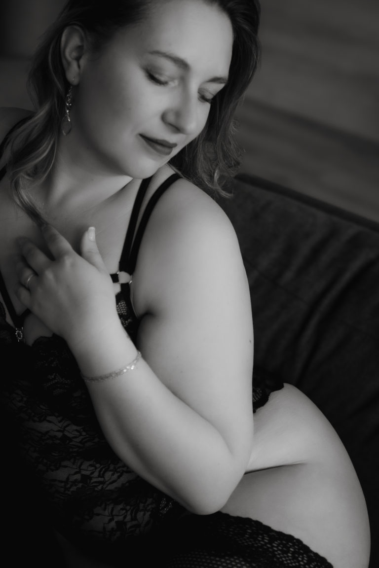 Photo en noir et blanc d'une femme en lingerie caressant son décolleté